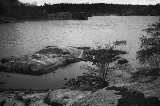 Kuva: Yleiskuva Alue A:sta, matalan vedenkorkeuden vuoksi osa rakennejäänteistä olivat vedenpinnan yläpuolella. Taka-alalla Vedaholmen. Kuva otettu tasanteelta läheltä saaren korkeinta kohtaa. Idästä Henrik Jansson 1997